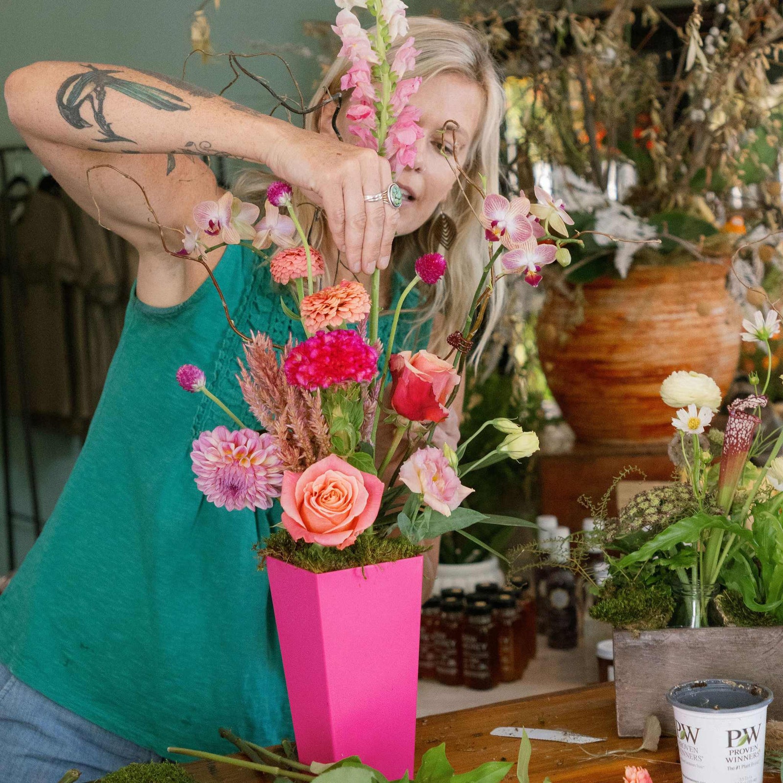 Florist arranging tall arrangment in raspberry tapered vase